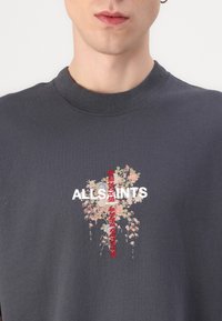 Camiseta de algodón gris con el texto blanco "ALLSAINTS" y bordado floral en tonos rosa y verde con acentos rojos. Diseño clásico de cuello redondo.