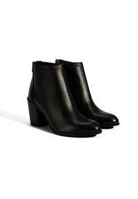 Bottines en cuir noir avec une texture lisse, bout pointu et un talon haut épais. Elles disposent d'une fermeture éclair à l'arrière.