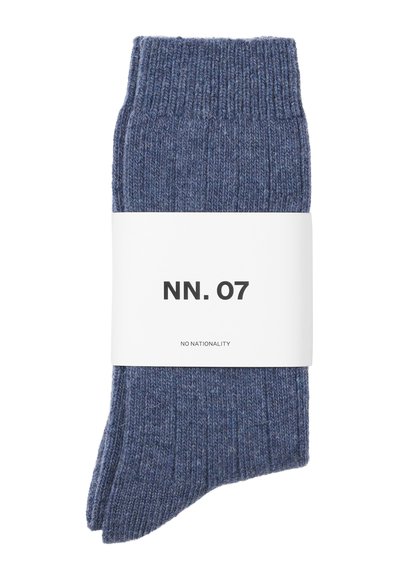 Calze blu a coste con orlo, presentate con una fascia di carta bianca etichettata "NN. 07" e "NO NATIONALITY". Texture morbida, senza motivi distintivi.