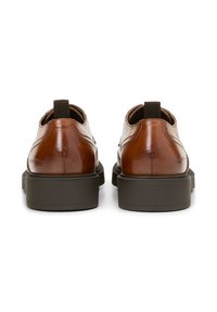 Chaussures en cuir marron avec une texture lisse, bout rond et semelles en caoutchouc noir. Comprend une languette et des coutures subtiles au niveau du talon.