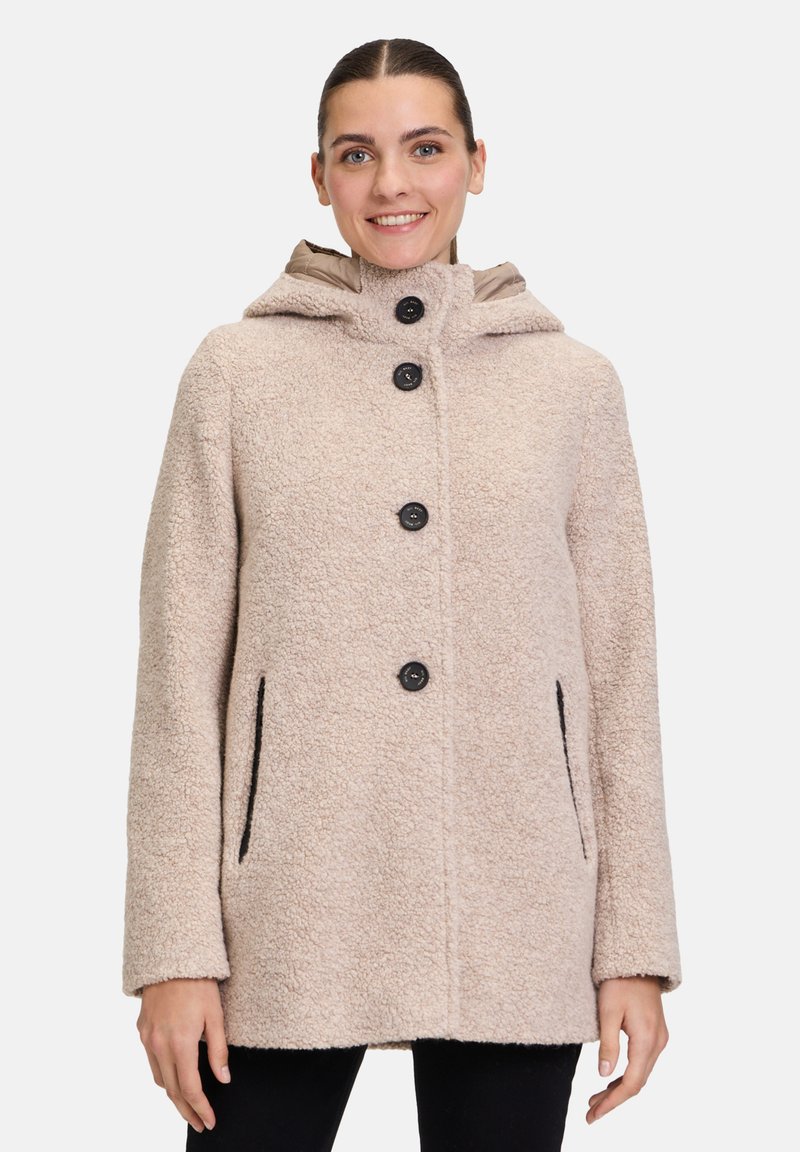 Beige strukturierter Mantel mit Kapuze, fünf schwarzen Knöpfen und Seitentaschen. Der Stoff wirkt weich und flauschig und hat einen lässigen, oversized Schnitt.