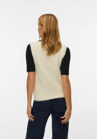 Sweter bez rękawów z kremowym korpusem i czarnymi krótkimi rękawami, o miękkiej fakturze i kontrastowym dołem. Prosty, nowoczesny design.