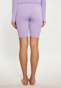 Lila fiets shorts gemaakt van gladde, rekbare stof. Heeft een middelhoge tailleband en een vormgevend pasvorm die eindigt boven de knie.