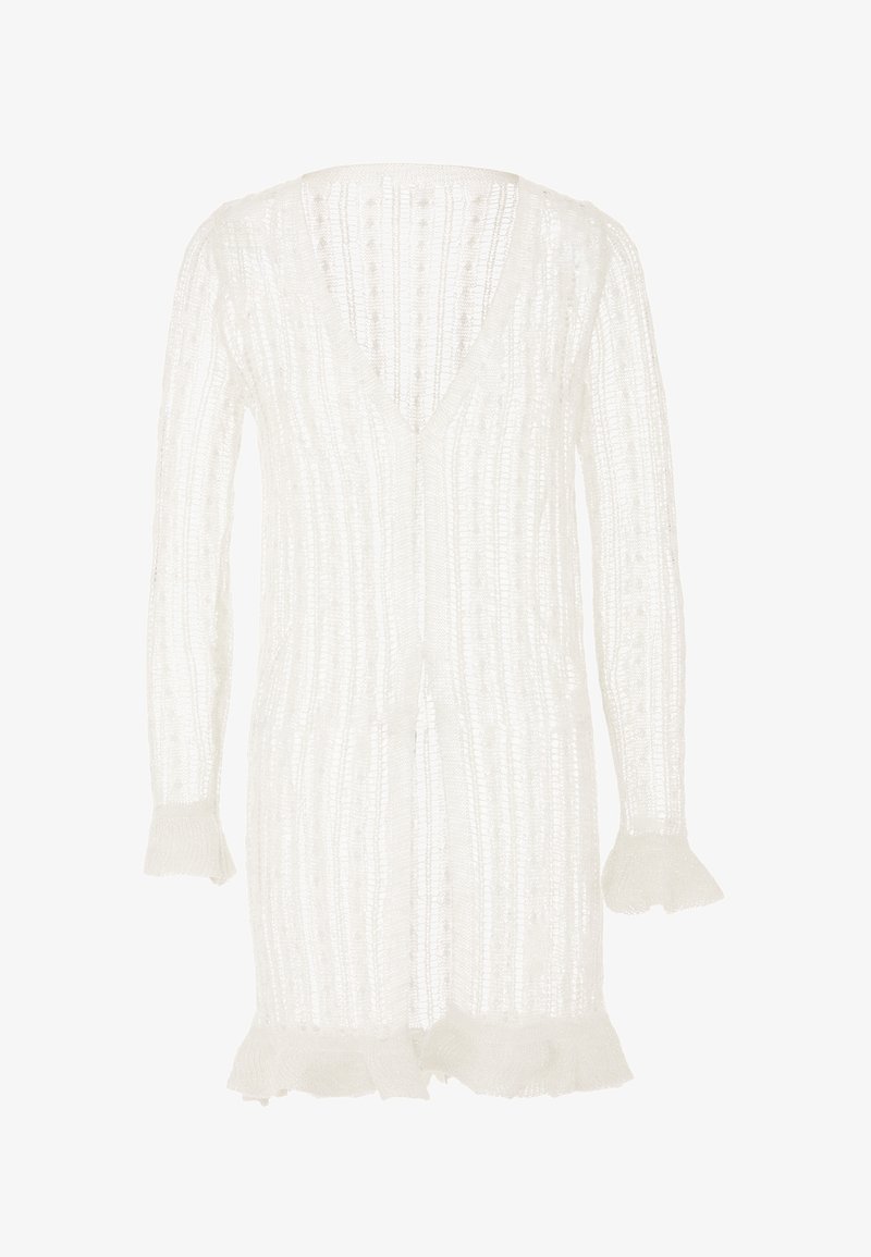 Cárdigan blanco con escote en V, silueta alargada, textura acanalada y puños acampanados con bordes frisados. Diseño ligero y abierto.