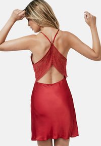Robe en satin rouge avec des détails en dentelle, des bretelles ajustables et un dos dégagé, offrant une texture lisse et une silhouette en A.