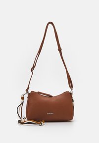 Hnědá kožená kabelka přes rameno s texturou, nastavitelným popruhem a dekorativním pleteným provazem v černé, bílé a hořčicové barvě, stříbrným zipem a logem "SURI FREY".