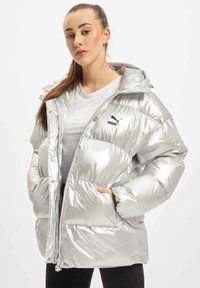 Sølv pufferjakke med en blank finish, med hætte, lynlåslukning og sidelommer. Inkluderer et sort Puma-logo på brystet.