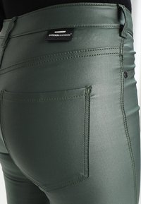 Gröna, slim fit denimjeans med en slät yta. Funktioner inkluderar bakfickor, detaljerad sömnad och en logotag på midjebandet.