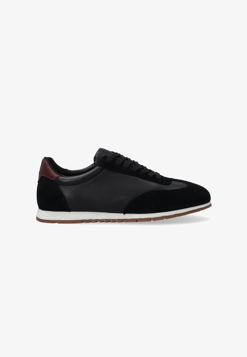 Schwarzer Sneaker aus Leder und Wildleder, mit strukturiertem Design, weißer Sohle und einem kastanienbraunen Akzent an der Ferse.
