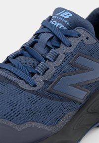 Baskets de course bleu marine avec une tige en mesh, des superpositions texturées, des lacets ronds et un audacieux logo "N" ; dotées d'une semelle rembourrée pour le confort.
