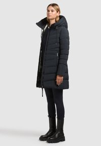 Gewatteerde zwarte parka met afneembare capuchon, ritssluiting en zijzakken, met een zachte textuur en een voering met een lichte glans.