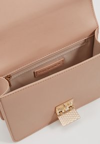 Borsa in finta pelle beige con chiusura in oro testurizzata, pattina aperta, scomparto con zip visibile e etichetta "Forever New" all'interno.