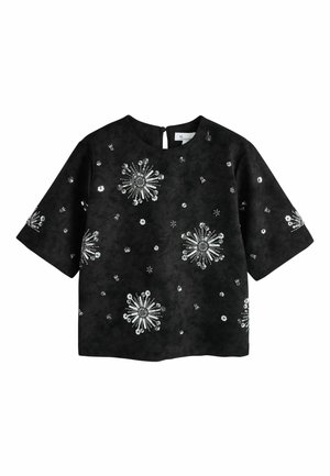 Schwarze Bluse mit kurzen Ärmeln und rundem Ausschnitt, verziert mit silbernen Pailletten in floralem Muster, die über Vorderseite und Ärmel verteilt sind.