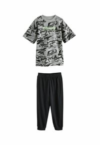Šedé tričko s krátkým rukávem v camouflage vzoru s černými tepláky. Tričko má kulatý výstřih, zatímco tepláky mají elastický pas a zúžené nohavice.