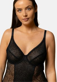 Lingerie en dentelle noire avec motif floral, doté d'un design en v, de bretelles réglables et de bords festonnés, mettant en valeur une texture transparente.