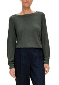 Pull à manches longues vert foncé avec un large col bateau et des poignets côtelés. Associé à un pantalon bleu marine à rayures fines. Texture douce.