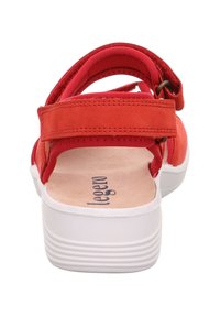 Czerwona sandał z regulowanymi paskami, wykonany z gładkiej skóry, z białą gumową podeszwą oraz teksturowaną wkładką z nazwą marki „legero”.