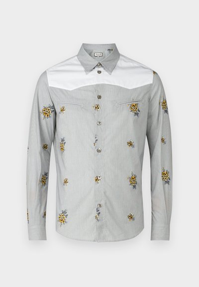 Camisa de manga larga en gris claro con cuello blanco, con bordado floral amarillo y botones plateados. Tejido suave con una textura lisa.
