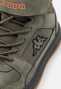 Höga sneakers i olivgrön med tyg- och mockamaterial. Har svart logotyp, texturerade snören och orange brandingdetalj. Brun gummisula.