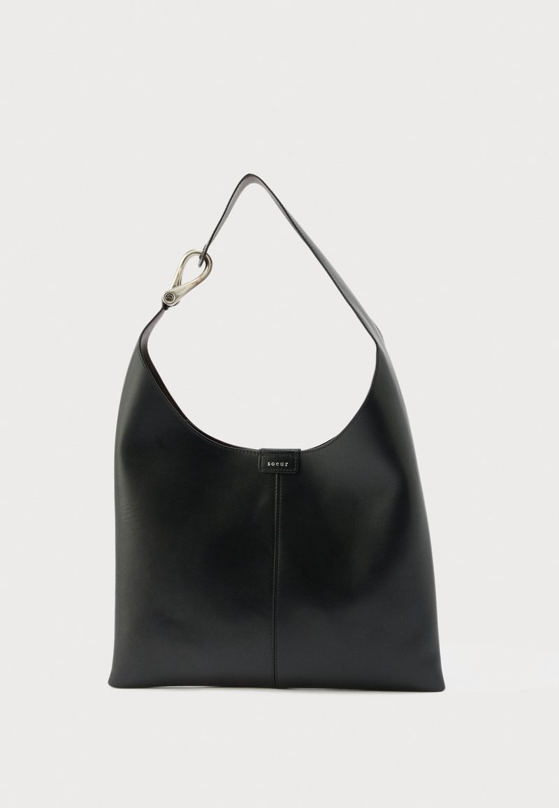 Sac à bandoulière en cuir noir avec une seule sangle et un détail de fermoir argenté, avec une petite étiquette de logo centrée sur un fond uni.