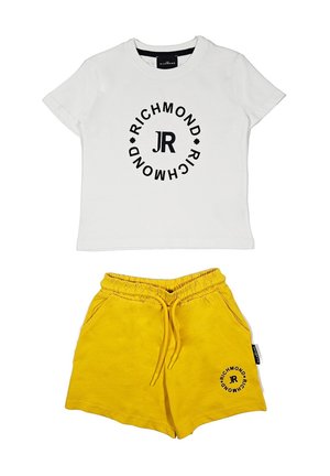 T-shirt bianca in cotone con logo circolare nero e testo "JR", abbinata a pantaloni corti gialli in cotone con cintura elastica e tasche laterali.