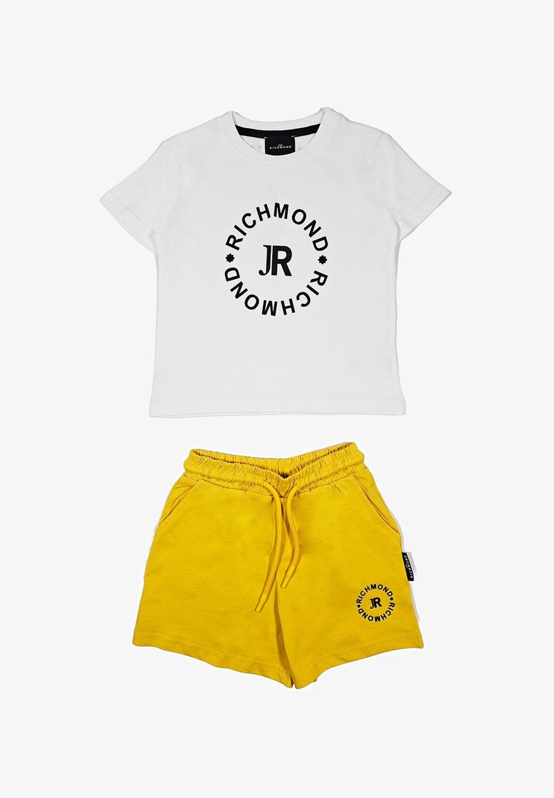 T-shirt bianca in cotone con logo circolare nero e testo "JR", abbinata a pantaloni corti gialli in cotone con cintura elastica e tasche laterali.