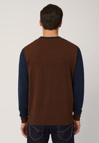 Gebreide trui met een bruine achterkant en marineblauwe mouwen, voorzien van geribbelde boorden en zoom, een gladde textuur en een ronde hals.