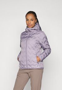 Veste isolante violette claire avec capuche, présentant un motif texturé, des poches avant et une fermeture éclair. Logo Columbia visible sur la poitrine.