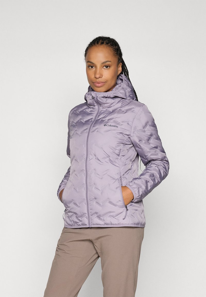 Veste isolante violette claire avec capuche, présentant un motif texturé, des poches avant et une fermeture éclair. Logo Columbia visible sur la poitrine.