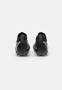 Scarpe da calcio nere con un design testurizzato, caratterizzate da accenti bianchi del logo, materiale morbido e molteplici tacchetti conici sulla suola nera.
