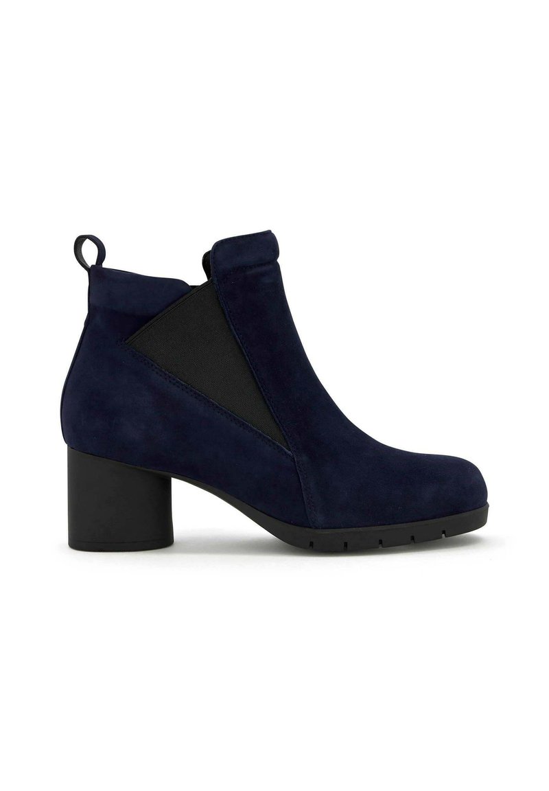 Bottines en daim bleu marine avec un talon carré, dotées de panneaux élastiques sur les côtés et d'une boucle à l'arrière pour un enfilement facile. Semelle en caoutchouc noire.