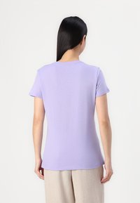 Fialové tričko s krátkým rukávem z měkké, lehké látky, s kulatým výstřihem a přiléhavým střihem. Bezšvový design na zadní straně.