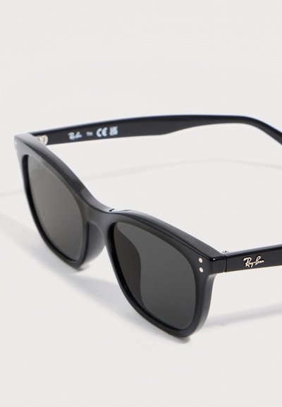 Черни слънчеви очила Ray-Ban с правоъгълни тъмни лещи и дебели лъскави рамки, показани под ъгъл на бял фон.