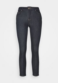 Jeans skinny de mezclilla azul oscuro con una cintura de altura media, que presentan un cierre de botón, cinco bolsillos y costuras amarillas sutiles.