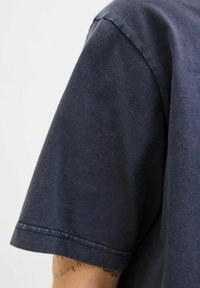 Donkerblauwe katoenen T-shirt met korte mouwen. Beschikt over een ronde halslijn en dubbel gestikte naden langs de randen. Gestructureerde stof.