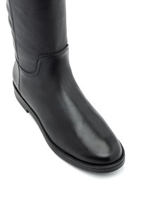 Czarne skórzane botki sięgające kolan o gładkim wykończeniu, zaokrąglonym nosku i minimalnym przeszyciu. Charakteryzują się niskim obcasem i opływowym kształtem.