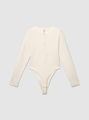 Body à manches longues couleur crème en tissu doux, avec un col arrondi et une patte de boutonnage à l'avant. Coupe slip à la base.
