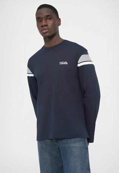 Μπλε ναυτικό μπλουζάκι με μακριά μανίκια και στρογγυλή λαιμόκοψη, με γκρι και λευκές οριζόντιες ρίγες στα μανίκια και μικρή λεπτομέρεια λογότυπου στο στήθος.