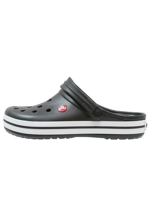 Sort Crocs clog med ventilationshuller, et rødt rundt logo, en hvid og sort stribet sål og en justerbar hælrem.
