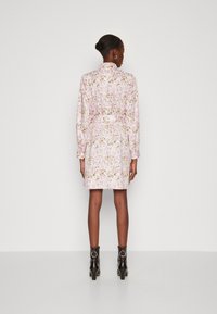 Φλοράλ φόρεμα σε ανοιχτό ροζ με χρυσές λεπτομέρειες, διαθέτει γιακά και μακριά μανίκια. Μαύρες γόβες με τακούνι και στρογγυλή μεταλλική λεπτομέρεια.