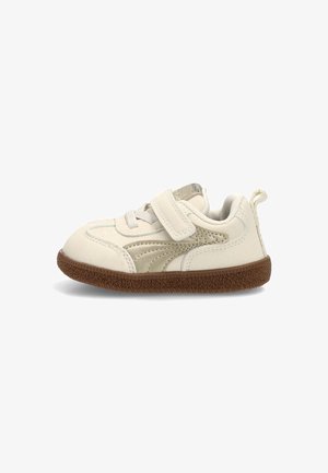 Zapatilla para niño pequeño color blanco roto con franja lateral beige, suela texturizada marrón, cierre de velcro y tira para tirar en el talón.