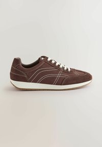 Baskets en daim marron avec des accents blancs, dotées d'un bout arrondi, de coutures décoratives et d'une semelle en caoutchouc texturée. Modèle à lacets.