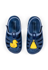 Blaue Gummisandalen mit gelbem Entchen und Sandburg auf jedem Riemen, mit Schnallenverschluss und strukturiertem Finish.