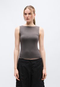 Haut gris sans manches avec une texture lisse, encolure arrondie et coupe ajustée, assorti à un pantalon cargo noir avec des détails zippés.