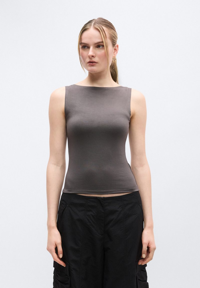 Haut gris sans manches avec une texture lisse, encolure arrondie et coupe ajustée, assorti à un pantalon cargo noir avec des détails zippés.