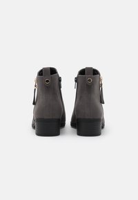 Szare zamszowe botki za kostkę z niskim obcasem, bocznymi zamkami błyskawicznymi i ozdobnymi chwostami, charakteryzujące się gładką fakturą i starannym detalem szwu.