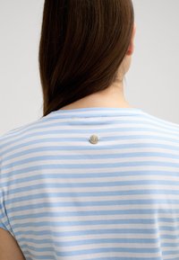 Gestreepte blauw-witte t-shirt met korte mouwen, met een zilveren logo-knopdetail aan de achterkant en een zachte, gladde textuur.