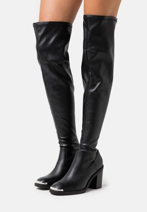 Černé, do kolen sahající, lesklé syntetické kožené boty s blokovým podpatkem a kovovým akcentem na špičce; hladká textura a tvarově přizpůsobený design.