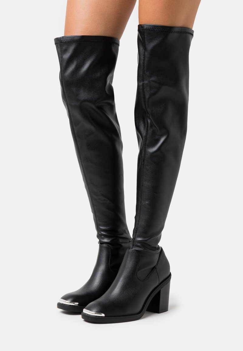 Stivali neri fino al ginocchio in pelle sintetica lucida, con tacco a blocco e accentuazione metallica sulla punta; texture liscia e design aderente.