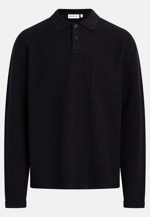 Polo noir à manches longues avec un motif en zigzag texturé, une patte à deux boutons et une poche sur la poitrine gauche. Confectionné dans un matériau doux.